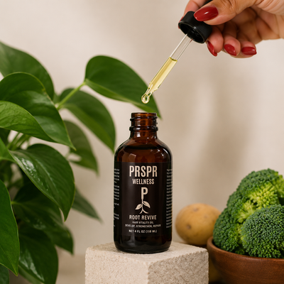 Hand holding a dropper applying Root Revive Hair Vitality Oil from an amber glass bottle, demonstrating a natural scalp treatment for nourishing the scalp, strengthening hair, and supporting healthier looking hair growth.