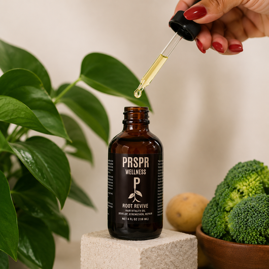 Hand holding a dropper applying Root Revive Hair Vitality Oil from an amber glass bottle, demonstrating a natural scalp treatment for nourishing the scalp, strengthening hair, and supporting healthier looking hair growth.